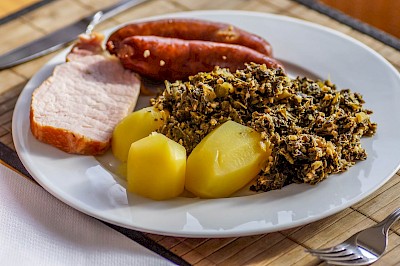 Kartoffeln, Grünkohl, Kassler und Pinkel auf einem Teller angerichtet