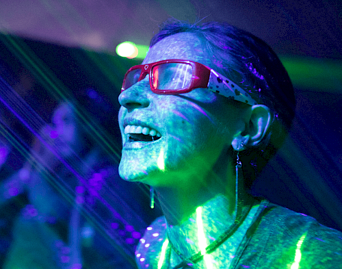 Begeisterte Frau mit Brille und Neonstrahlen im Gesicht.