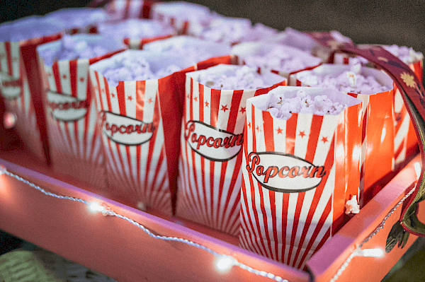 Rot-weiß gestreifte Popcorntüten, die aneinandergereiht und voll mit Popcorn sind